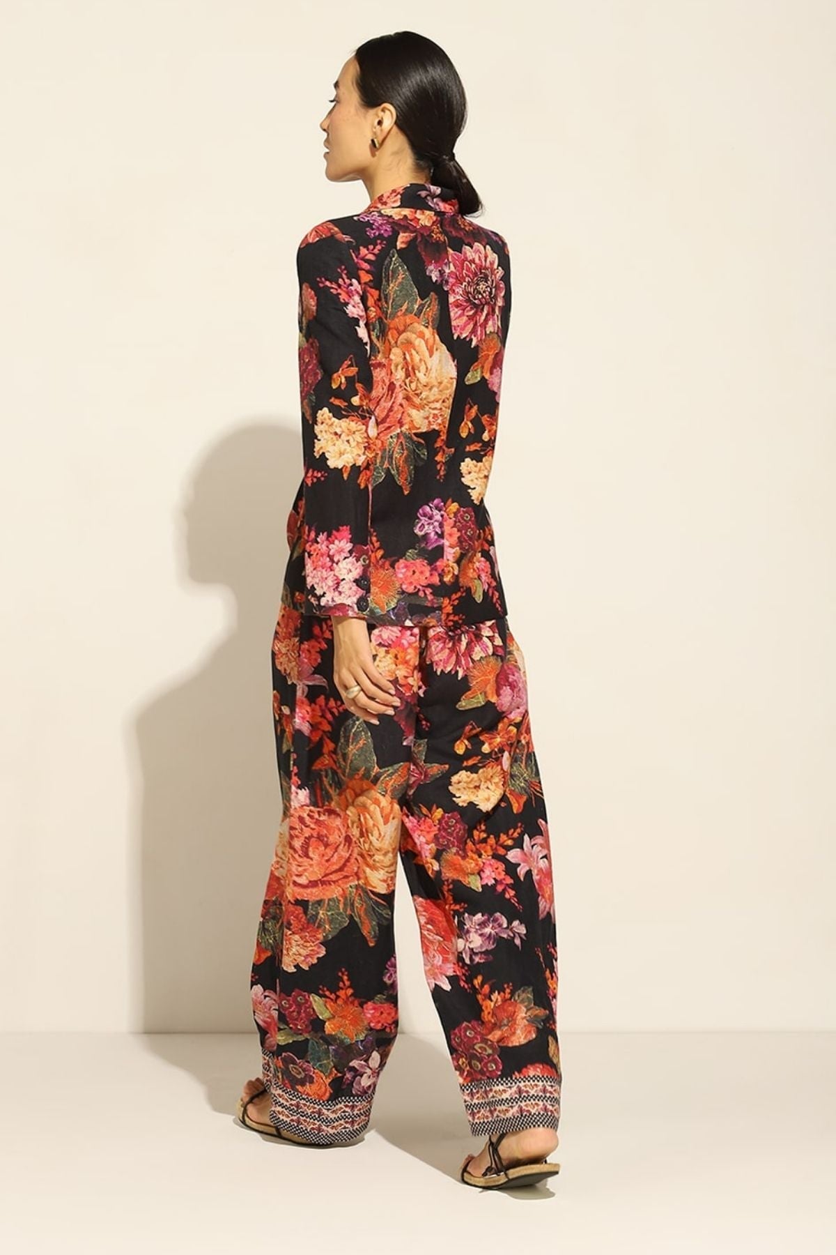 A person wearing a satin blend jacket with a floral pattern, in multicolor, featuring a notched lapel collar and straight sleeves.