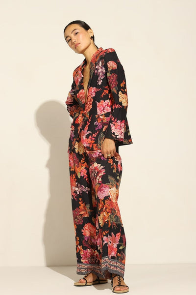 A person wearing a satin blend jacket with a floral pattern, in multicolor, featuring a notched lapel collar and straight sleeves.