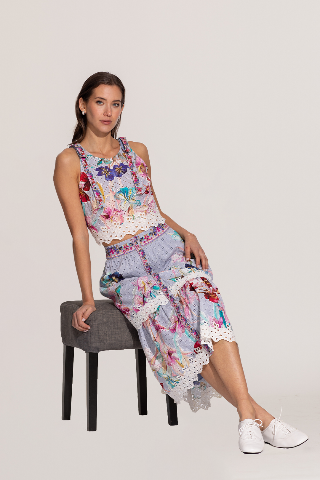 A sleeveless halter crop top and a skirt with a floral print, featuring eyelet details and embroidery on the hemline.
