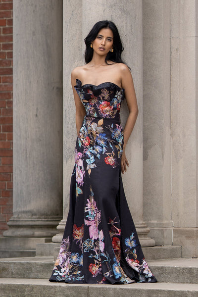 Ranna Gill’s Sera Gown in black viscose jacquard with strapless ruffle neckline, floral print, thigh-high slit, and sequin detailing.