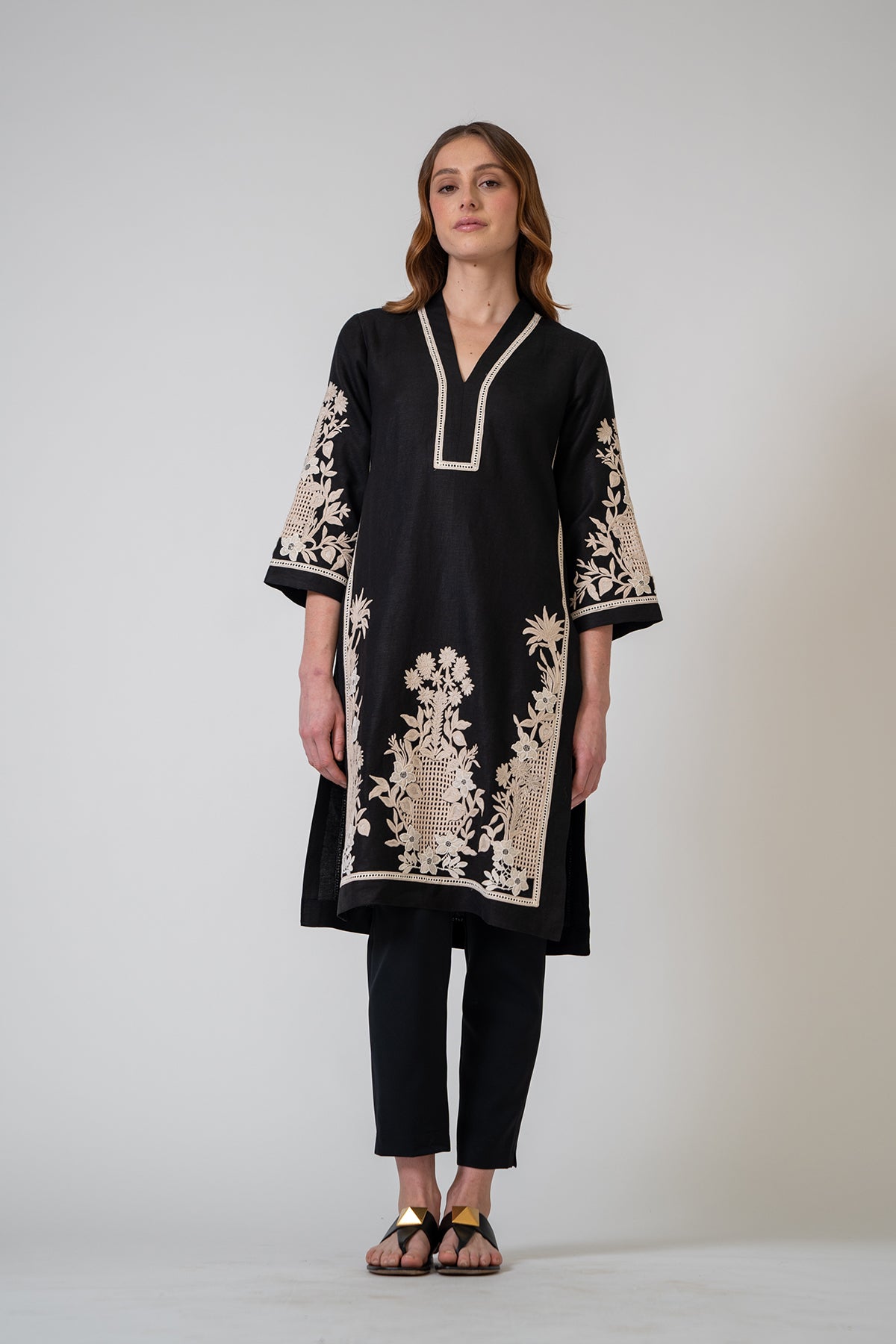 Woman wearing a black embroidered kurta with white patterns on a plain background