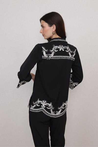 Ranna Gill Casa Blouse wearing a black blouse with white floral and geometric patterns.