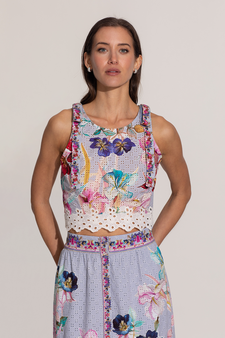 A sleeveless halter crop top and a skirt with a floral print, featuring eyelet details and embroidery on the hemline.