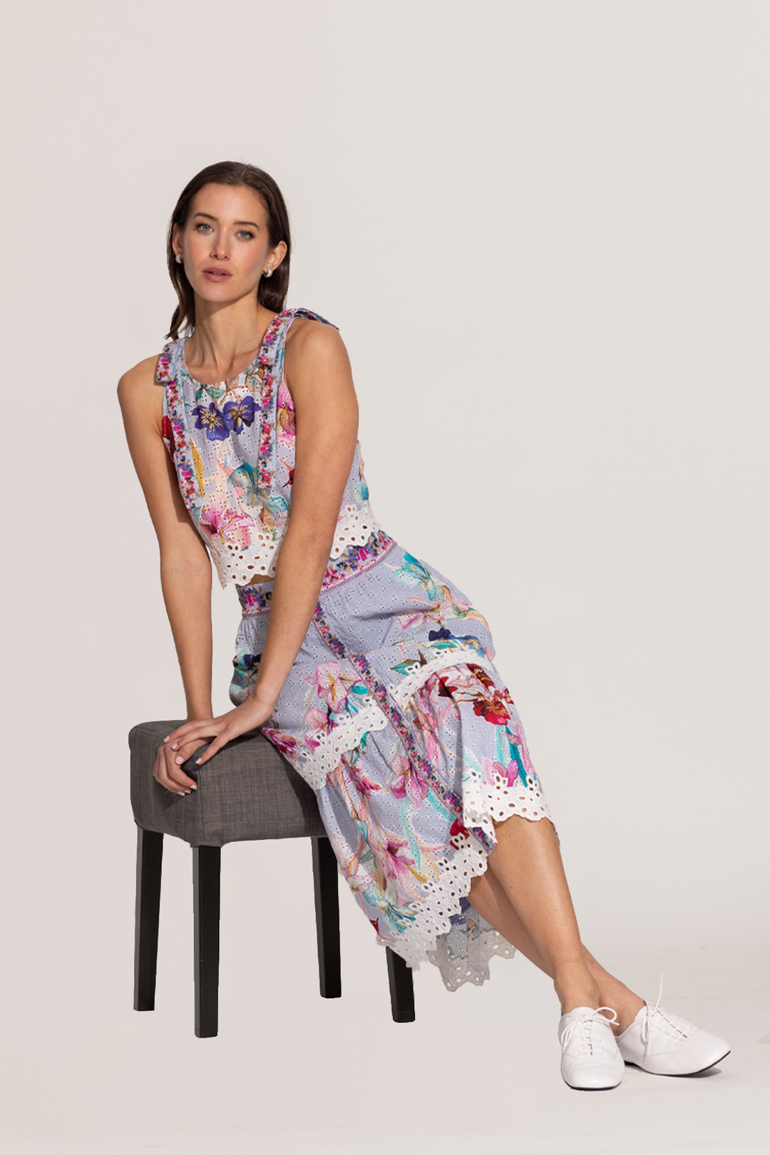 A sleeveless halter crop top and a skirt with a floral print, featuring eyelet details and embroidery on the hemline.