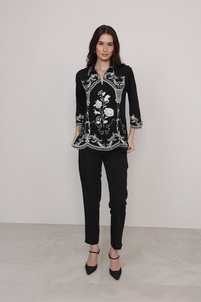 Ranna Gill Casa Blouse wearing a black blouse with white floral and geometric patterns.