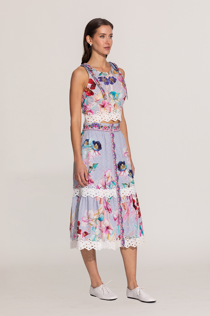 A sleeveless halter crop top and a skirt with a floral print, featuring eyelet details and embroidery on the hemline.