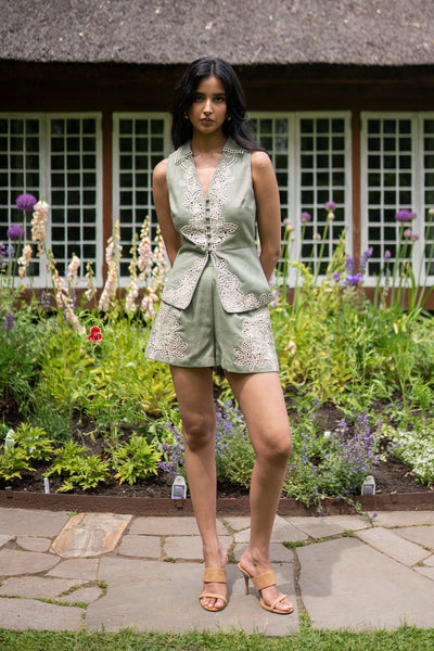 Eli sage green high-waist shorts with front pleats and floral Schiffli embroidery on hem by Ranna Gill.