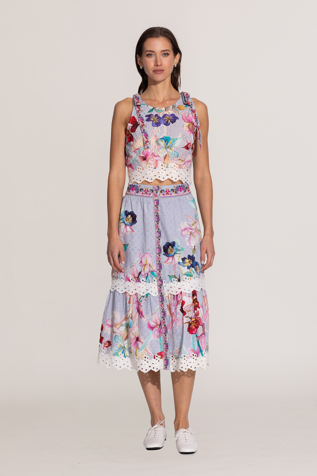 A sleeveless halter crop top and a skirt with a floral print, featuring eyelet details and embroidery on the hemline.