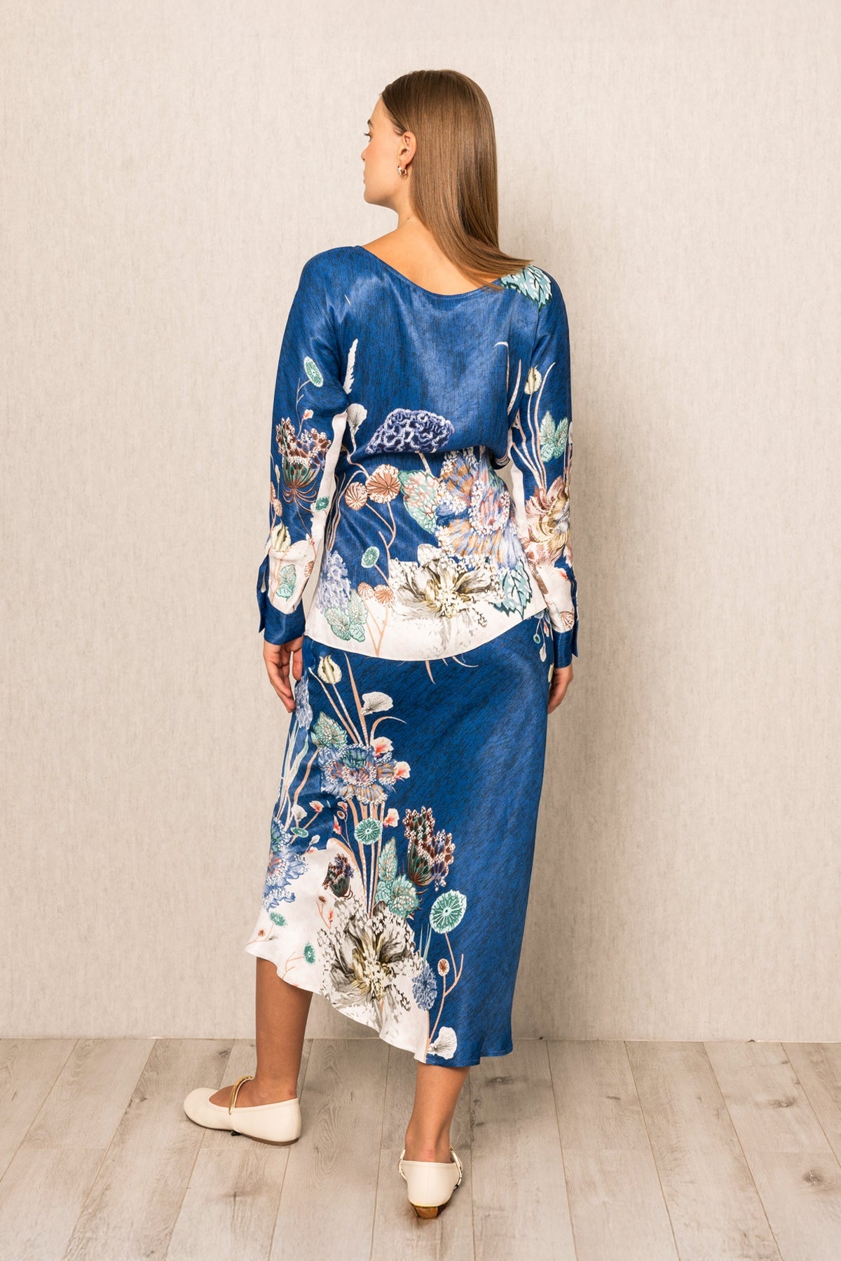 Woman wearing a blue floral dress against a plain background