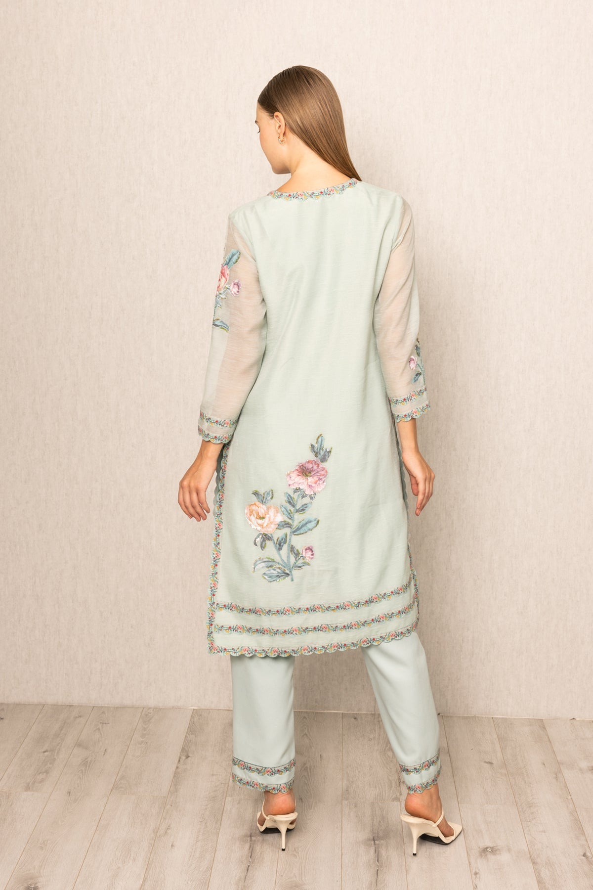 Woman wearing a light blue embroidered outfit with floral patterns 