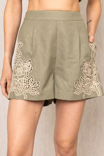 Eli sage green high-waist shorts with front pleats and floral Schiffli embroidery on hem by Ranna Gill.
