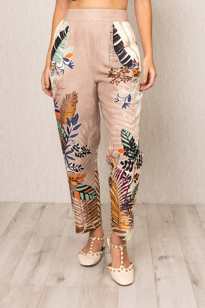 Front view of Ranna Gill Liora Rara Pants in beige linen-viscose fabric with vibrant tropical botanical prints in orange, green, blue, and black, featuring straight fit and elastic waistband.