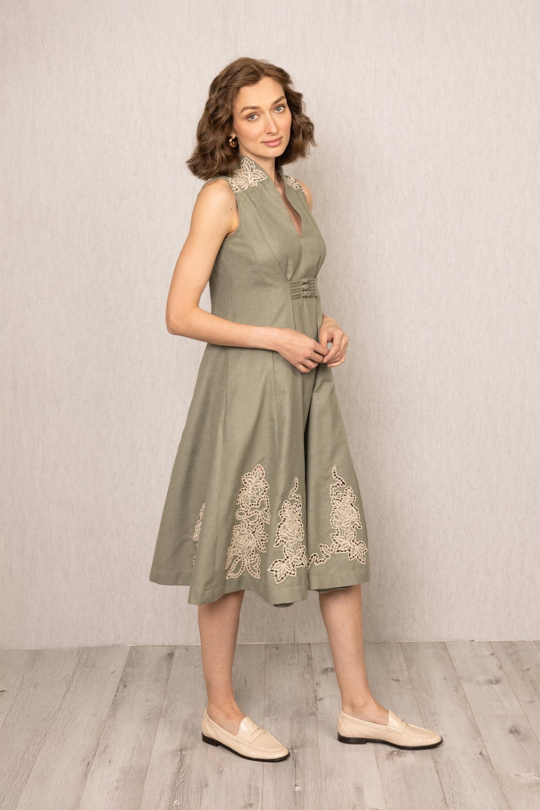 Woman wearing a green dress with lace details against a plain background
