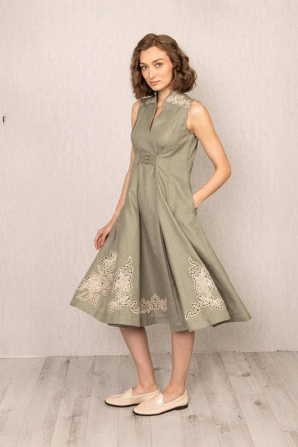 Woman wearing a green dress with lace details against a plain background