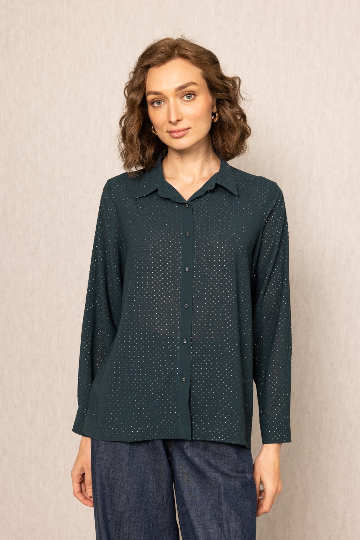 Woman wearing a dark green patterned shirt against a beige background