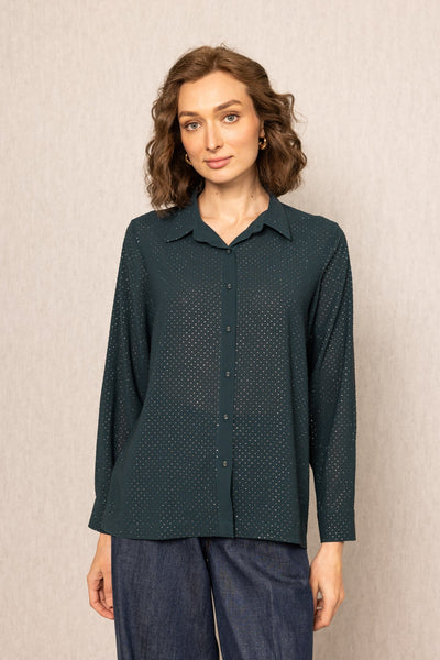 Woman wearing a dark green patterned shirt against a beige background