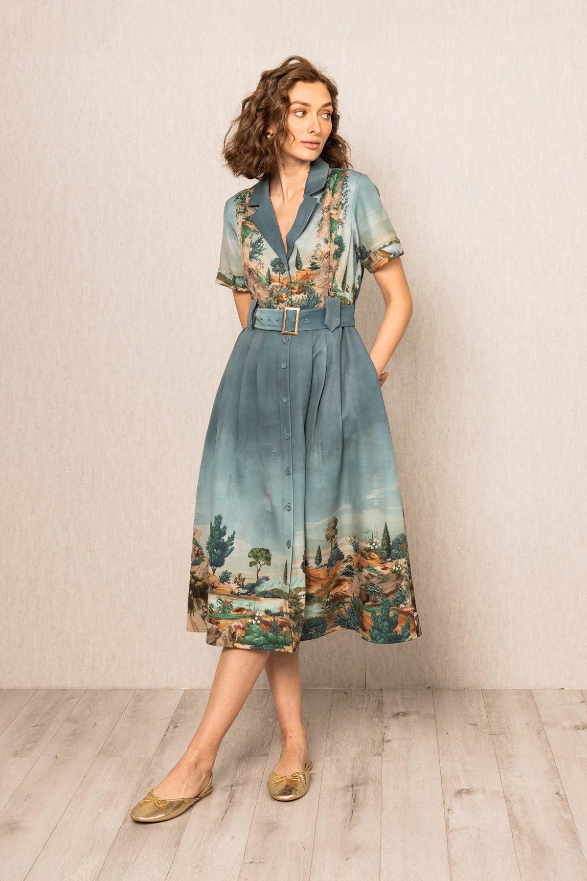 Woman wearing a floral dress with a belt against a plain background