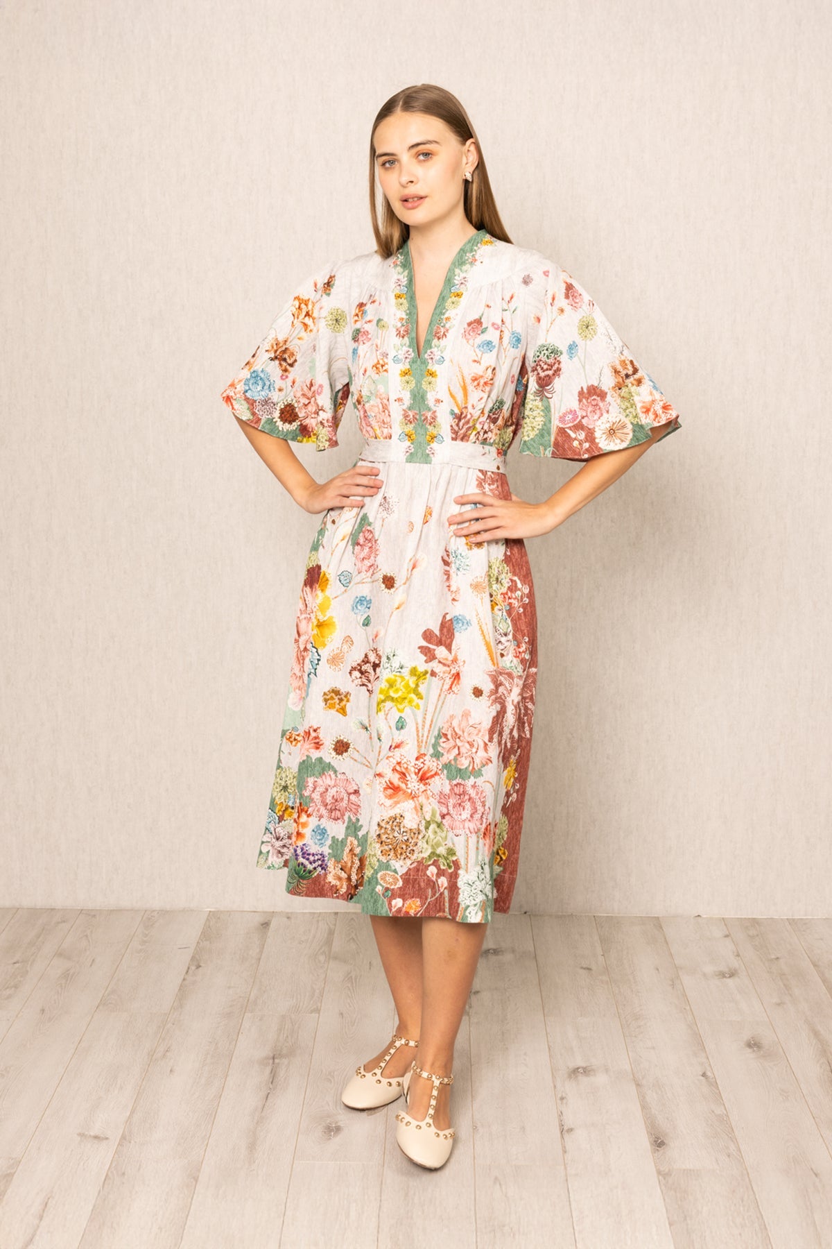 Woman wearing a floral dress standing against a plain background