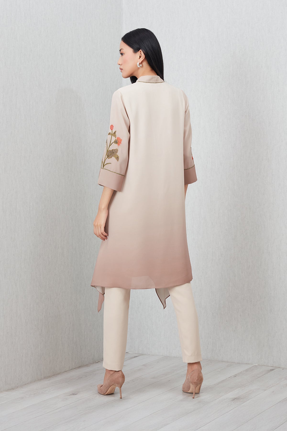 Beige Azara Tunic by Ranna Gill with floral embroidery, V-neckline, 3/4 sleeves, and handkerchief hem.