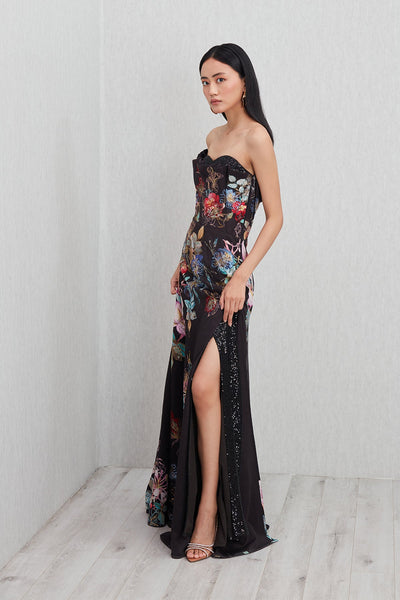 Ranna Gill’s Sera Gown in black viscose jacquard with strapless ruffle neckline, floral print, thigh-high slit, and sequin detailing.