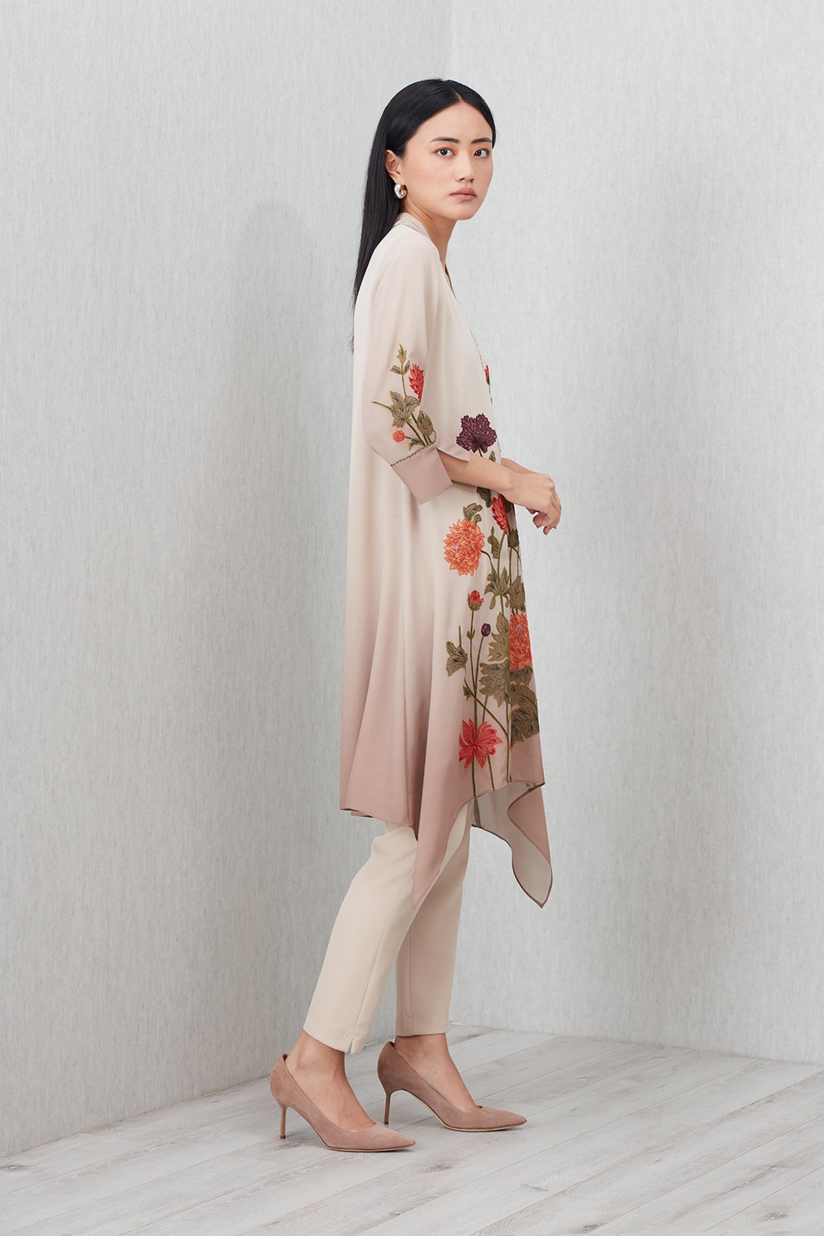 Beige Azara Tunic by Ranna Gill with floral embroidery, V-neckline, 3/4 sleeves, and handkerchief hem.