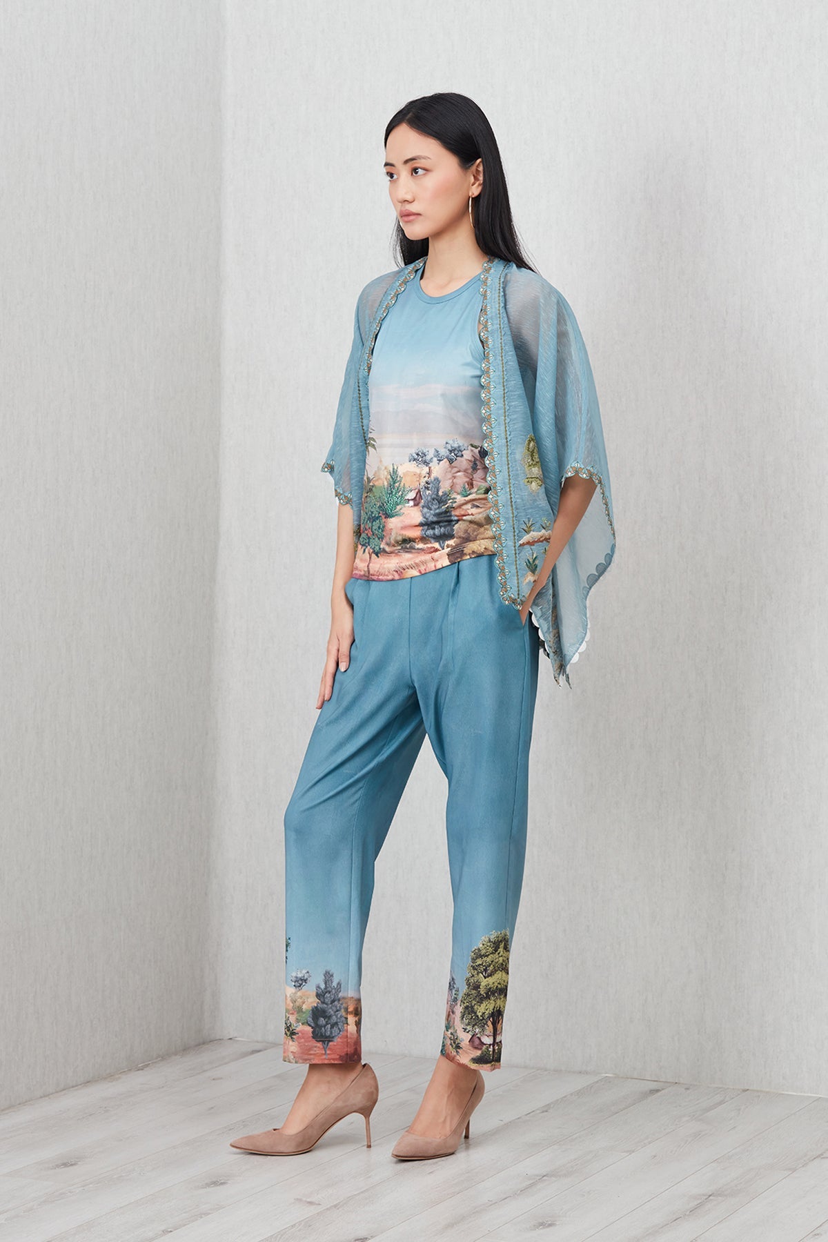 Woman wearing a blue outfit with floral patterns on a plain background