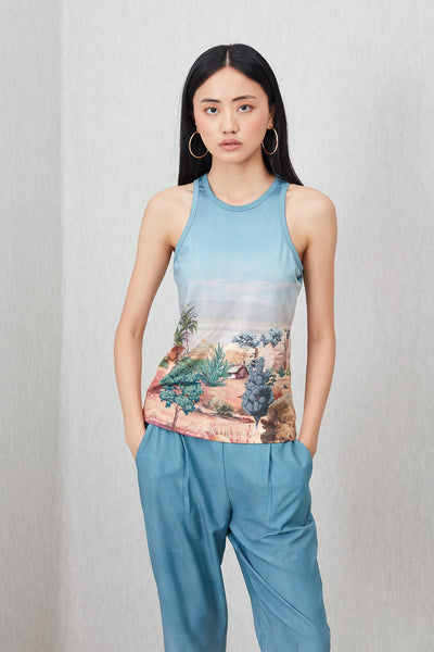 Woman wearing a sleeveless top with a nature print and matching pants on a plain background