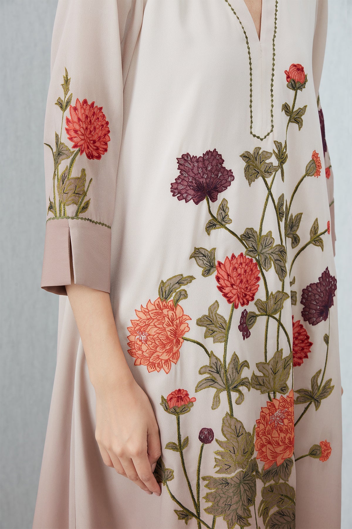 Beige Azara Tunic by Ranna Gill with floral embroidery, V-neckline, 3/4 sleeves, and handkerchief hem.